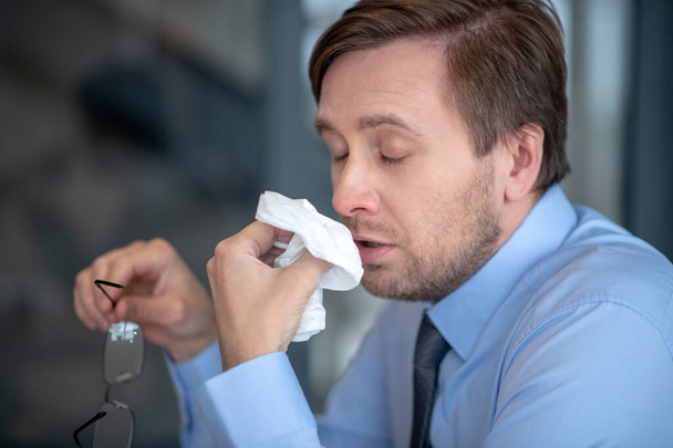 baard volwassen man niezen tijdens het werken in kantoor - Foto, afbeelding