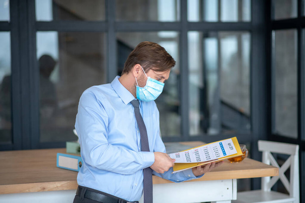 Busy businessman wearing mask checking his schedule - Foto, imagen