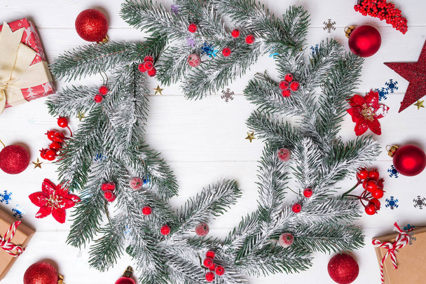 Χριστουγεννιάτικη ευχετήρια κάρτα με διακόσμηση και κλαδί ελάτης σε λευκό ξύλινο φόντο. Κάτοψη με χώρο αντιγραφής για τους χαιρετισμούς σας - Φωτογραφία, εικόνα