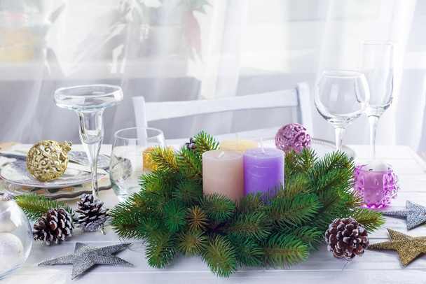 Coloque el ajuste de mesa para la mesa blanca de Navidad con elementos de decoración púrpura y corona verde árbol de Navidad
 - Foto, imagen