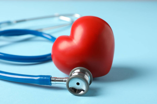 Stethoskop und Herz auf blauem Hintergrund, Nahaufnahme - Foto, Bild