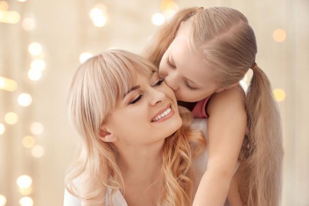 Young woman with her daughter on light background - Photo, Image