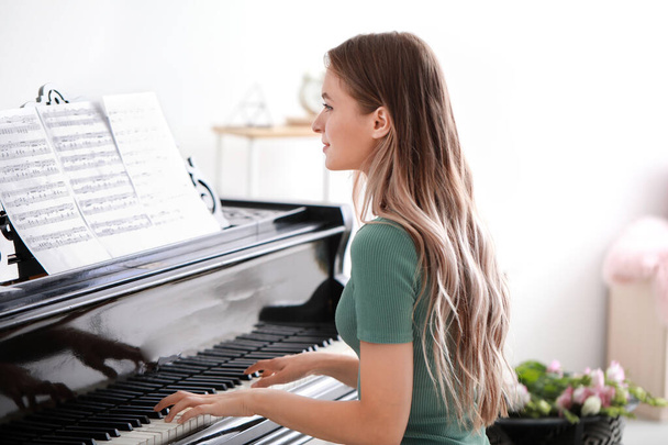 Young woman playing grand piano at home - Foto, imagen