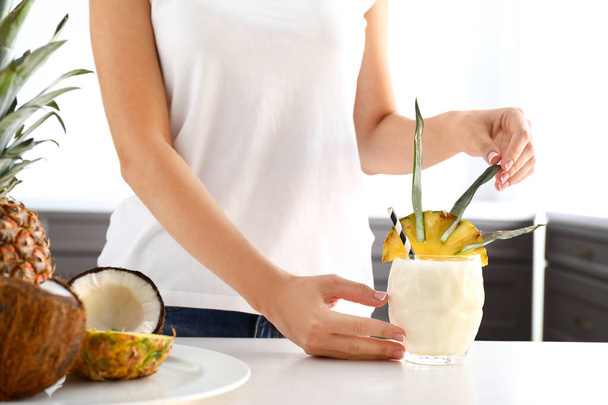 Kobieta ze szklanką smacznego koktajlu Pina Colada w kuchni - Zdjęcie, obraz