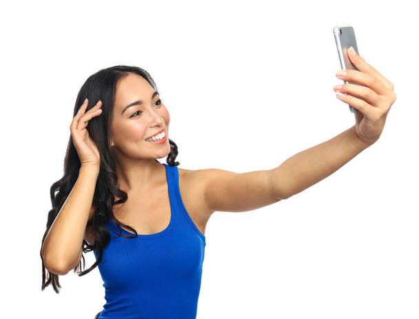Όμορφη Ασιάτισσα γυναίκα που παίρνει selfie σε λευκό φόντο - Φωτογραφία, εικόνα