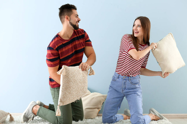 Portrait of happy young couple fighting with pillows indoors - Foto, immagini