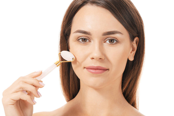 Mulher bonita com ferramenta de massagem facial no fundo branco
 - Foto, Imagem