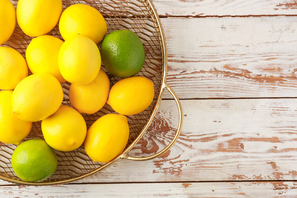 Tray with ripe lemons and limes on wooden background - Photo, Image