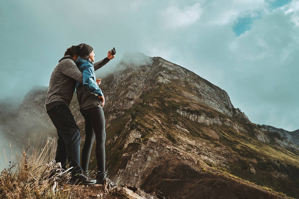 a young couple hugges on a cliff and takes a selfi photo - Photo, Image