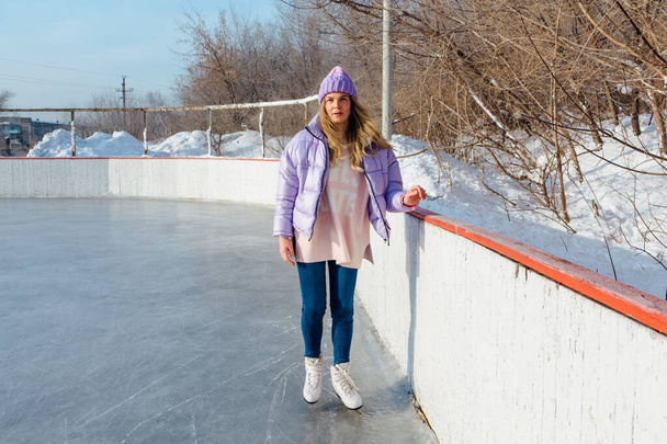 Lovely young woman with riding ice skates on the ice rink. - Φωτογραφία, εικόνα