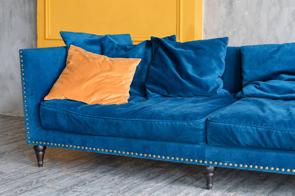 Comfortabele klassieke blauwe Bank met oranje kussens in eenvoudig minimalistisch appartement - Foto, afbeelding