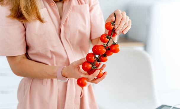 Beautiful red tomatoes on a branch in hands. - Foto, imagen