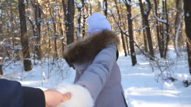 Dívka drží muže za ruku a běží zasněženým lesem. Následuj mě, jak mladá žena tahá svého přítele v zimním lese. Scénický zimní prostředí. Pojem vztah. Pov Slow mo Close up - Záběry, video