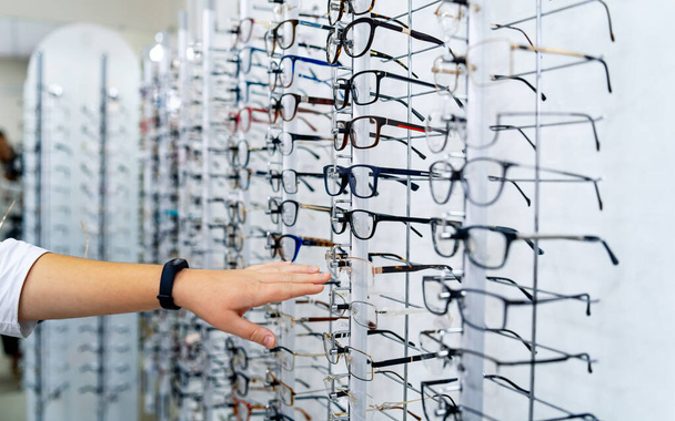 Row of glasses at an opticians. Eyeglasses shop. Stand with spectacles. - 写真・画像
