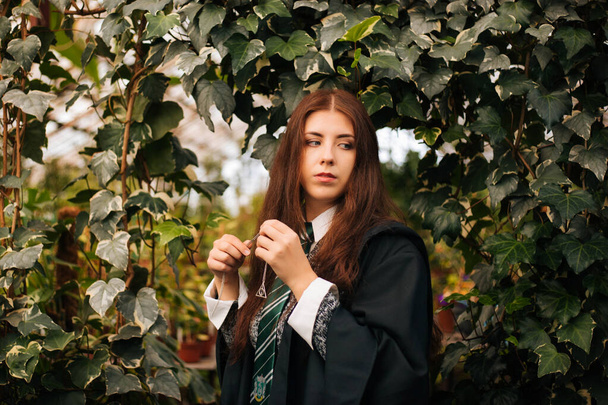Kopeysk, Chelyabinsk / Russia - 10/02/2019: A girl from the school of young wizards with a medallion in her hands. Sorceress on the background of greenery in the greenhouse - cosplay. - Fotografie, Obrázek