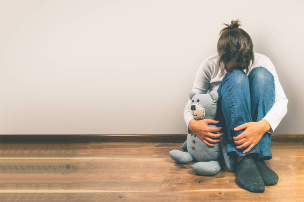 Prenatal loss concept - depressed woman holding teddy bear toy - 写真・画像