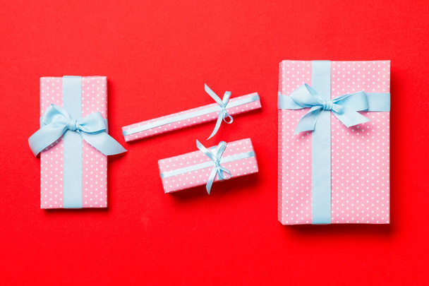 Top view Χριστουγεννιάτικο κουτί δώρου με μπλε τόξο σε κόκκινο φόντο - Φωτογραφία, εικόνα