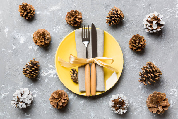 New Year set of plate and utensil on cement background. Top view of holiday dinner decorated with pine cones. Christmas time concept - Photo, Image