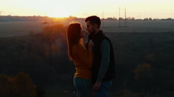 Sylwetka uroczej pary patrzą sobie w oczy przed pocałunkiem o zachodzie słońca - Materiał filmowy, wideo