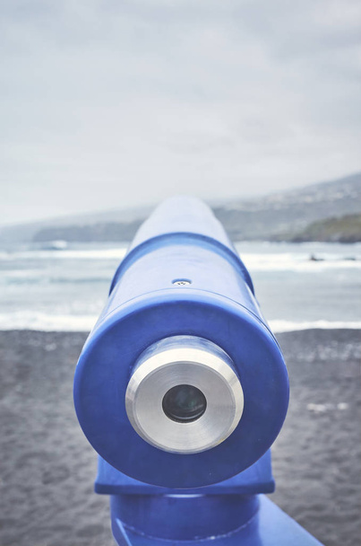 Télescope pointant vers l'horizon sur une plage volcanique
. - Photo, image