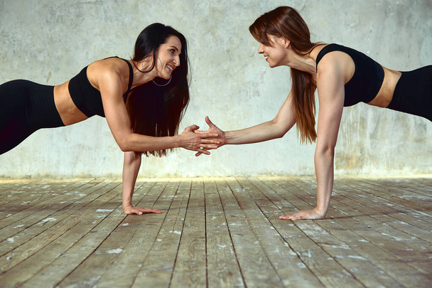 Две молодые женщины делают парные упражнения в тренажерном зале. позируя и улыбаясь перед камерой, получайте удовольствие, отличную атмосферу
. - Фото, изображение