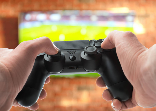 Gamepad in the hands. Playing soccer video games - Fotó, kép