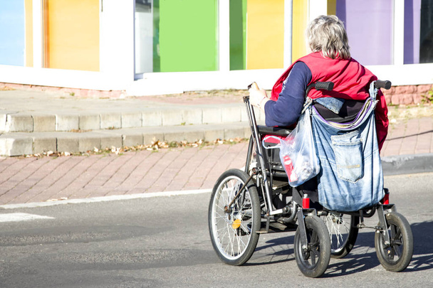 Γυναίκα σε αναπηρική καρέκλα. Κοινωνική προστασία. Υποστήριξη για άτομα με ειδικές ανάγκες. Κοινωνικά προβλήματα. Ο γέρος σε αναπηρική καρέκλα. Άτομα με ειδικές ανάγκες στο δρόμο για το σπίτι. - Φωτογραφία, εικόνα