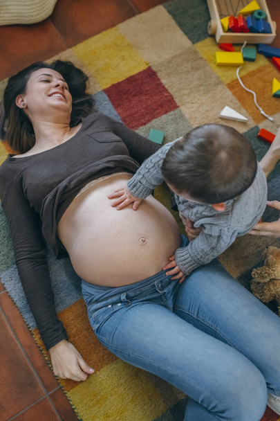 A terhes anya hasát simogatta kisgyermek - Fotó, kép