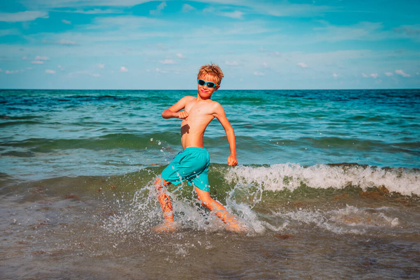 happy young boy run and play with waves on beach - Фото, зображення