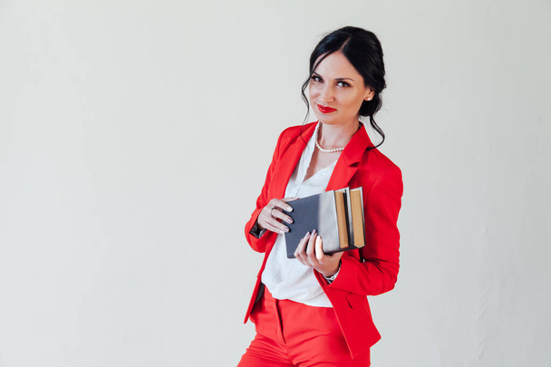 портрет красивой женщины с книгами в красном деловом костюме в офисе
 - Фото, изображение