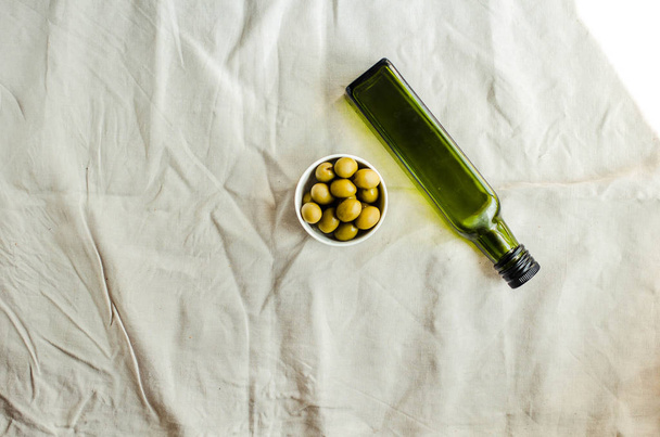 Extra virgin olive oil in a green glass bottle and green olives. - Foto, Imagem