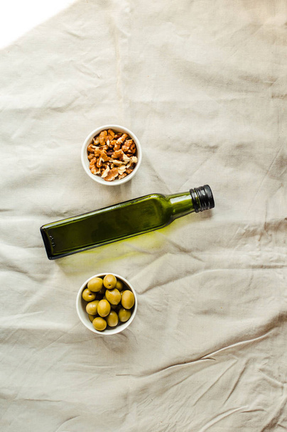 Extra virgin Walnut oil in a green glass bottle and green olives - Fotoğraf, Görsel