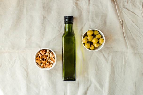Extra virgin Walnut oil in a green glass bottle and green olives - Foto, Imagen
