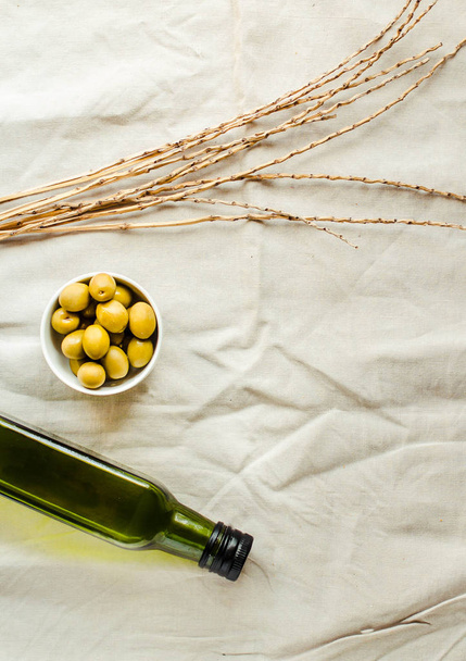 Extra virgin olive oil in a green glass bottle and green olives. - Fotó, kép
