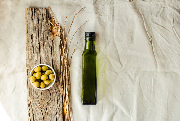 Extra virgin olive oil in a green glass bottle and green olives. - Photo, Image