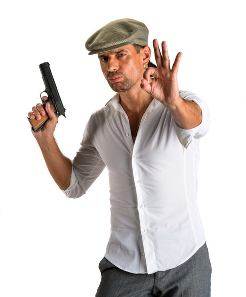 όμορφος άνδρας στο καπάκι με ένα πυροβόλο όπλο - Φωτογραφία, εικόνα