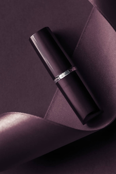Luxusní rtěnka a hedvábná stuha na tmavě fialové dovolené backgroun - Fotografie, Obrázek
