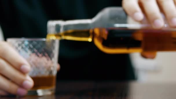 Mladý opilec nalévá a pije whisky ze sklenice a usíná na stole, poloprázdnou láhev whisky v popředí - Záběry, video