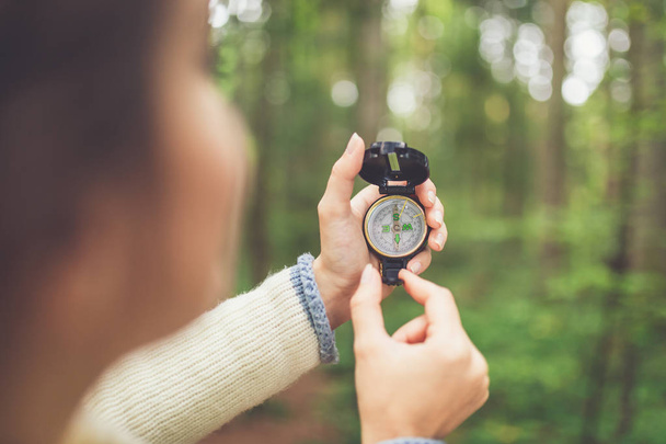Hiker traveler using compass in nature. Tourist girl trying to find her way out of the forest. - Fotografie, Obrázek