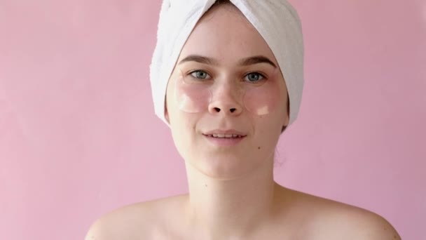 Giovane donna con rilievi di collagene sotto gli occhi su sfondo rosa. Spa, cura della pelle, bellezza, cosmetici, concetto di benessere
 - Filmati, video
