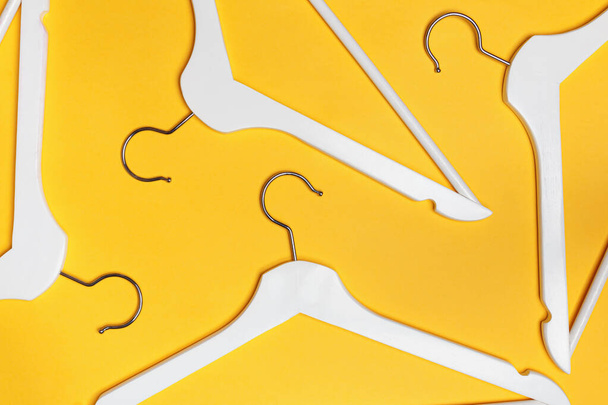 White hangers on a yellow background. Flat lay. Top view. The concept of shopping, sales, storage - Фото, изображение