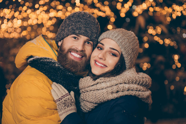 Merry christmas. Photo of two people guy lady in love visit city illuminated park newyear x-mas evening frosty weather stand close wear winter jackets scarfs hats outdoors - 写真・画像