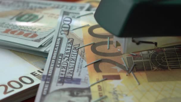 A tűzőgép vaskapcsokkal rögzíti a dollár és az euró bankjegyeket. Gémkapcsos tűzőgép a bankjegyek hátoldalán. Hamis pénz. - Felvétel, videó