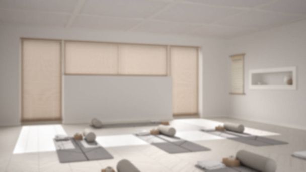 Rozmyte tło wnętrza: puste studio jogi, otwarta przestrzeń z matami, poduszkami i akcesoriami, parkiet ze śledzia, duże okno, gotowe do ćwiczeń jogi, sala medytacyjna - Zdjęcie, obraz