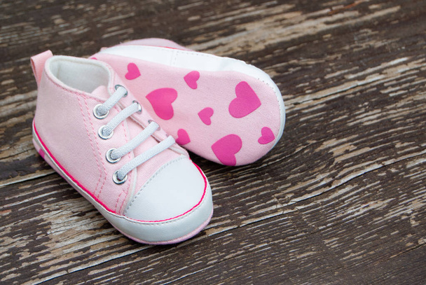 Baby girl pink shoes on wooden background - 写真・画像