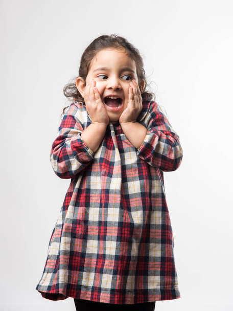 Happy / excited Indian Little kid girl with open mouth looking with surprised expressions. Standing isolated over white background - Photo, Image