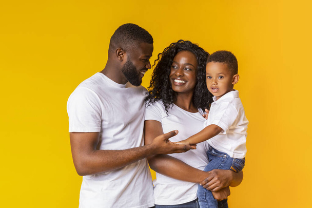 Portrait de parents aimants avec un petit fils sur fond jaune
 - Photo, image