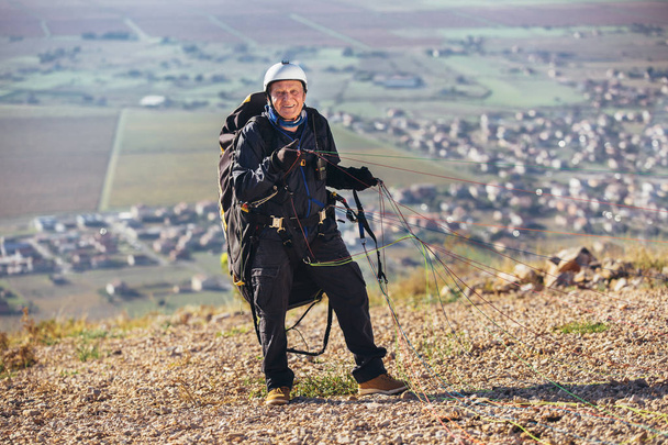 Senior paraglider op de grond prepairs om te vliegen. - Foto, afbeelding