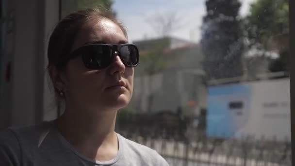 Touristin sitzt am Fenster und fährt mit Straßenbahn in die Innenstadt - Filmmaterial, Video