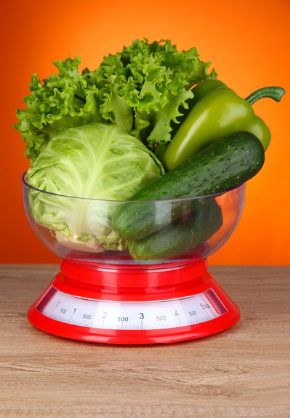 Fresh vegetables in scales on table on orange background - Photo, image